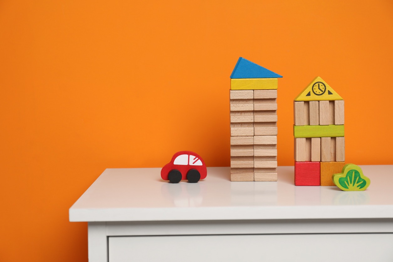 recorte mesa con juguetes de madera y fondo naranja